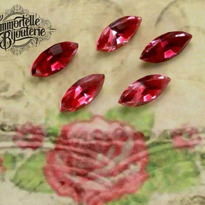 May include: Five marquise-shaped, red glass rhinestones. The rhinestones are faceted and have a high shine.