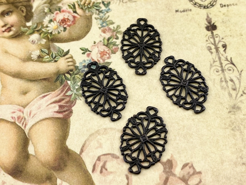 Puede incluir: Cuatro abalorios de filigrana de metal negro en forma de &oacute;valo con un dise&ntilde;o decorativo. Los abalorios tienen un bucle en la parte superior para sujetarlos a joyas u otras manualidades.
