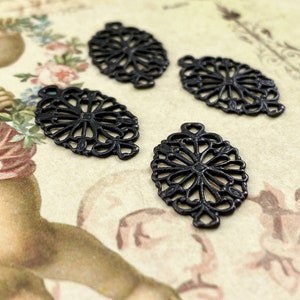 Puede incluir: Cuatro abalorios ovalados de filigrana met&aacute;lica negra con un delicado dise&ntilde;o floral.