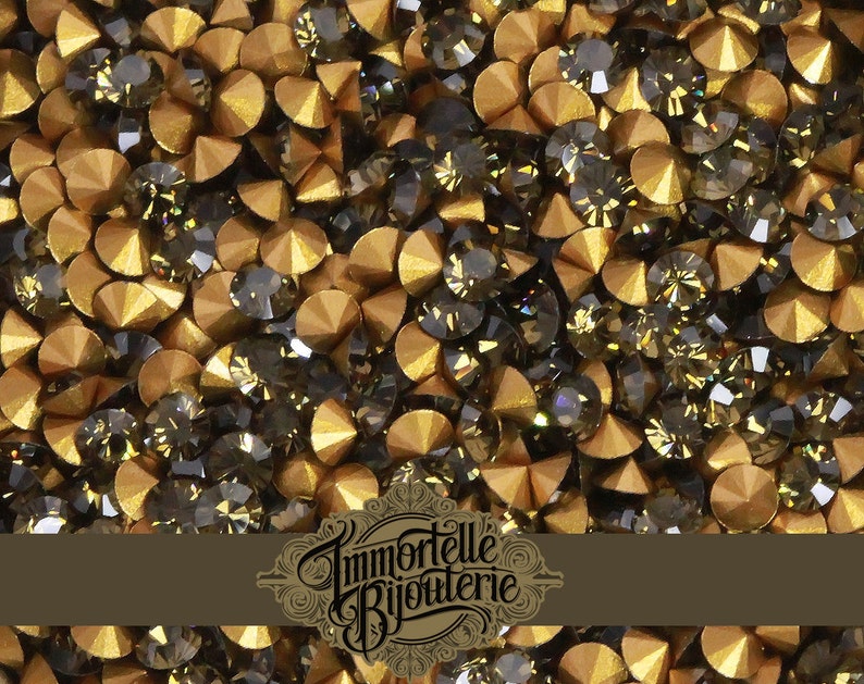May include: A close-up image of a large quantity of small, round, gold and dark gray rhinestones. The rhinestones are scattered randomly and appear to be for crafting or jewelry making.