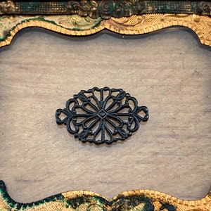 Puede incluir: Una filigrana decorativa de metal negro con un dise&ntilde;o floral, sobre un fondo dorado y verde.