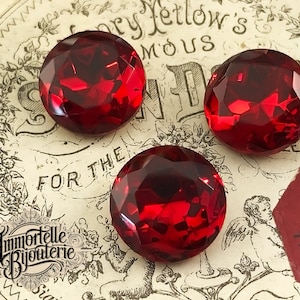 Peut inclure: Trois cabochons en verre rouge avec un design facetté. Les cabochons sont ronds et ont une finition brillante.