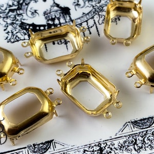 May include: Six gold-toned metal settings for bezel settings. Each setting has a rectangular shape with rounded corners and three loops for attaching to a jewelry piece.