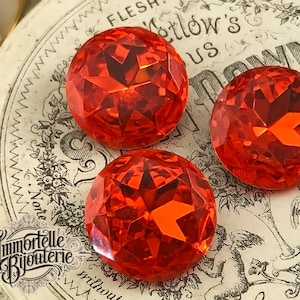 May include: Three large, faceted, red glass buttons. The buttons are round and have a shiny, reflective surface.