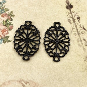 Puede incluir: Dos abalorios de metal filigranado negro en forma de flor con un centro circular. Los abalorios son de forma ovalada y tienen un dise&ntilde;o delicado e intrincado.
