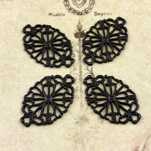 Puede incluir: Cuatro adornos de metal negro filigranados con un dise&ntilde;o floral. Cada adorno tiene forma ovalada con un centro decorativo.