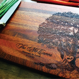 May include: Personalized wooden cutting board with a tree design and the text "The McCanns Rooted in Love 2-16-90" and a heart with the initials "M&P" engraved in the tree trunk.
