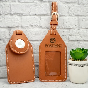 May include: Two brown leather luggage tags with white stitching. One tag has a clear window and the text "POSITANO ANALYTICAL RESOURCES". The other tag has a silver apple logo.