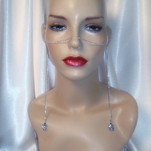 May include: A silver chain nose ring with rhinestones and dangling charms. The charms are small and feature a spider design.