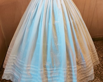 May include: A white cotton petticoat with a lace trim and multiple layers of ruffles. The petticoat is a full circle skirt with a fitted waistband.