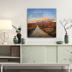 May include: A canvas print with a quote about the journey being more important than the destination. The quote is "It is good to have an end to journey towards, but it is the journey that matters in the end." The image shows a dirt road leading through a forest with fall foliage.