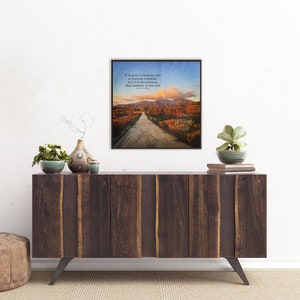 May include: A framed print with a quote about the importance of the journey, featuring a scenic road winding through a forest with colorful autumn foliage. The quote reads: "It is good to have an end to journey toward, but it is the journey that matters in the end."