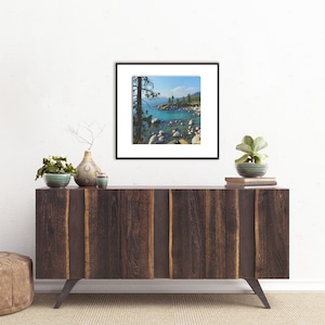 May include: A framed photograph of a scenic landscape with a lake, rocks, and trees. The lake is a vibrant blue-green color, and the rocks are scattered along the shoreline. The trees are green and lush, and the sky is a clear blue.