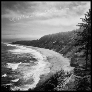 May include: A black and white photograph of a rocky coastline with a sandy beach and crashing waves. The photo was taken from a high vantage point, looking down at the beach. The sky is cloudy and the water is choppy. The text "&copy;MeT lookinforlight63@gmail.com" is visible in the upper right corner of the image.