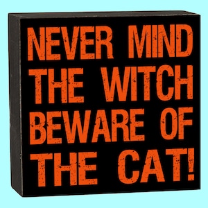 May include: Black wooden sign with white trim and the text "NEVER MIND THE WITCH BEWARE OF THE CAT!" in orange.