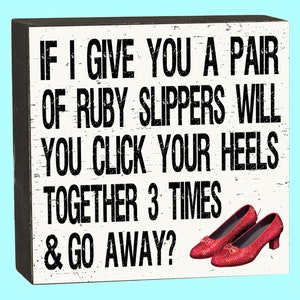 May include: A white wooden sign with black text that reads "IF I GIVE YOU A PAIR OF RUBY SLIPPERS WILL YOU CLICK YOUR HEELS TOGETHER 3 TIMES & GO AWAY?"  Two red sparkly ruby slippers are shown at the bottom of the sign.