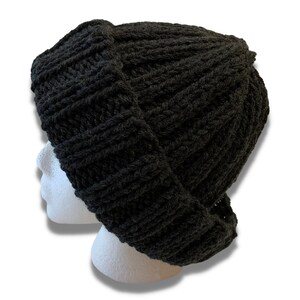 May include: A black knitted beanie with a slouchy fit. The beanie is made from thick, chunky yarn and has a ribbed texture.