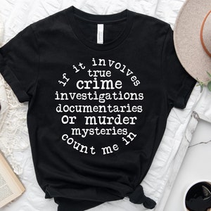 May include: Black t-shirt with white text that reads "If it involves true crime investigations, documentaries or murder mysteries, count me in."