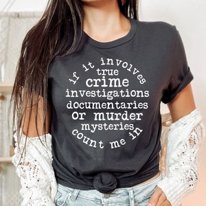 May include: Black t-shirt with white text that reads "If it involves true crime investigations, documentaries, or murder mysteries, count me in."