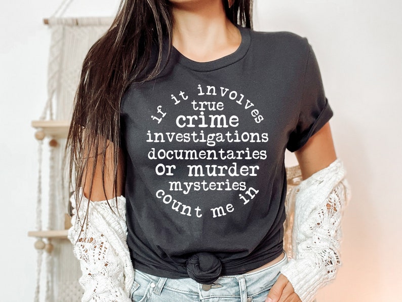 May include: Black t-shirt with white text that reads "If it involves true crime investigations, documentaries, or murder mysteries, count me in."