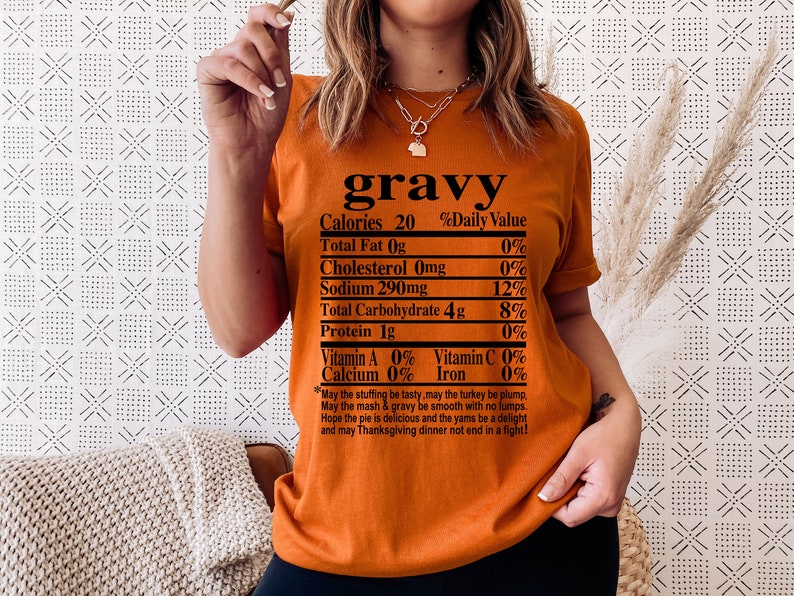 May include: Orange t-shirt with the word "gravy" at the top, followed by a nutrition facts label. The label lists calories, fat, cholesterol, sodium, carbohydrates, and protein. A Thanksgiving-themed poem is printed at the bottom.