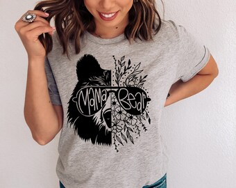 May include: A gray t-shirt with a black and white graphic of a bear wearing sunglasses and floral accents. The text "Mama Bear" is printed on the shirt.