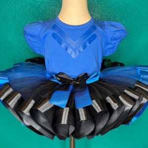 May include: A white ceramic mug with a black handle and the text "But First, Coffee" in a black, handwritten-style font. The mug is on a white surface.