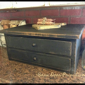 May include: A black wooden box with two drawers and a distressed finish. The box is sitting on a granite countertop. The text "Barn Door Primitives" is visible in the bottom right corner of the image.
