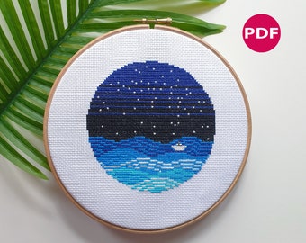 May include: A cross-stitch pattern of a dark blue night sky with white stars and a small white sailboat on a blue and turquoise ocean.