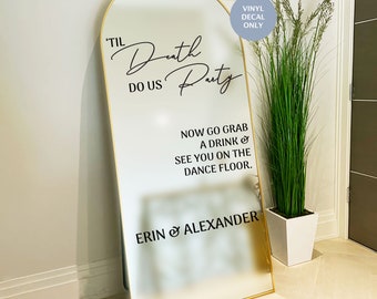 May include: An arched floor mirror with a gold frame featuring black vinyl decal text that reads 'TIL Death DO US Party, NOW GO GRAB A DRINK & SEE YOU ON THE DANCE FLOOR. ERIN & ALEXANDER'. A circular blue sticker in the corner states VINYL DECAL ONLY.
