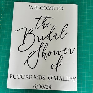 May include: White sign with black text that reads "Welcome to the Bridal Shower of Future Mrs. O'Malley 6/30/24".