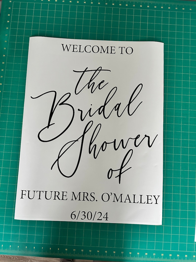 May include: White sign with black text that reads "Welcome to the Bridal Shower of Future Mrs. O'Malley 6/30/24".