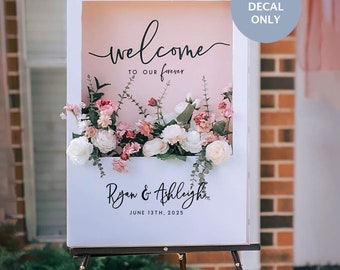 May include: White welcome sign with a pink background and floral accents. The sign reads "welcome to our forever" and "Ryan & Ashleigh June 13th, 2025".