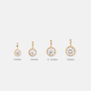 May include: Four gold pendants with a clear round stone in the center. The pendants are 3mm, 4mm, 4.5mm, and 5mm in size.