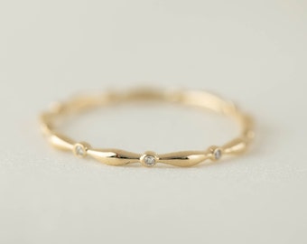 May include: A delicate gold band ring with a wavy design and small diamonds set into the band.