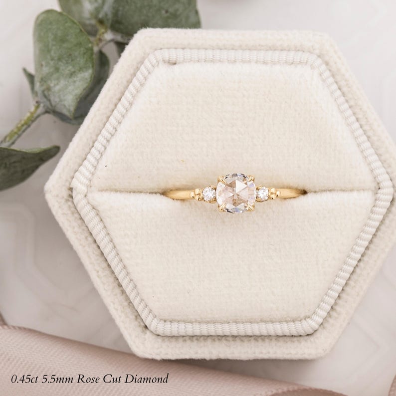 May include: A gold ring with a 0.45ct 5.5mm rose cut diamond and two smaller accent diamonds. The ring is in a white velvet ring box.