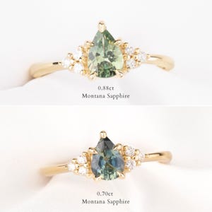 May include: Two gold rings with pear-shaped Montana sapphires. The top ring features a 0.88ct green sapphire, and the bottom ring has a 0.70ct blue-green sapphire. Both rings have small, round accent stones.