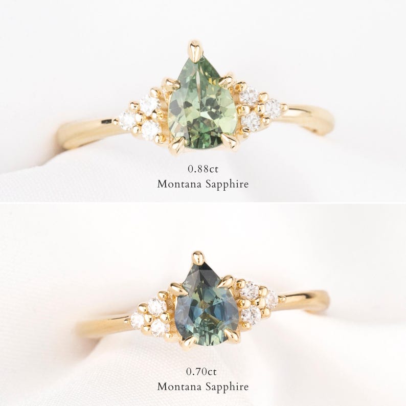 May include: Two gold rings with pear-shaped Montana sapphires. The top ring features a 0.88ct green sapphire, and the bottom ring has a 0.70ct blue-green sapphire. Both rings have small, round accent stones.