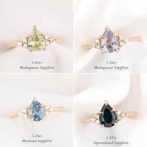 May include: Four gold rings with pear-shaped gemstones and small accent stones. The gemstones are green, light purple, blue, and dark blue. Each ring has text indicating the carat weight and sapphire origin.