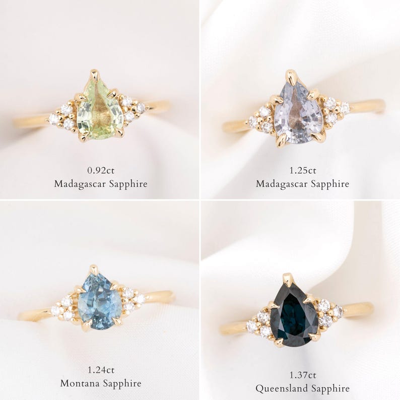 May include: Four gold rings with pear-shaped gemstones and small accent stones. The gemstones are green, light purple, blue, and dark blue. Each ring has text indicating the carat weight and sapphire origin.