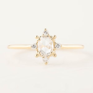 May include: A gold ring with a large oval-shaped clear gemstone surrounded by smaller clear gemstones.