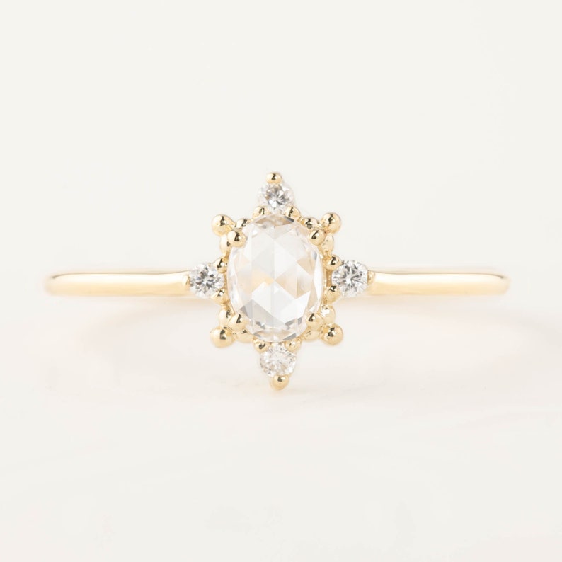 May include: A gold ring with a large oval-shaped clear gemstone surrounded by smaller clear gemstones.