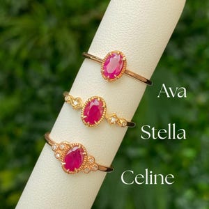 May include: Three gold rings with red oval gemstones and small diamonds. The rings are labeled "Ava", "Stella", and "Celine".