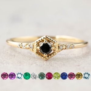 Op de afbeelding: Een gouden ring met een zwarte edelsteen in een geometrisch ontwerp. De ring is versierd met kleine diamanten.
