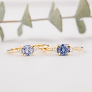 Op de afbeelding: Twee gouden ringen met een lichtblauwe edelsteen en twee kleinere witte edelstenen op elke ring.