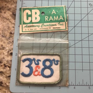 May include: A green and white patch with the text "3 & 8" in blue and orange lettering. The patch is labeled "CB RAMA Accessory Creations, Inc. P.O. Box 487 DUNBAR, W. 26504"