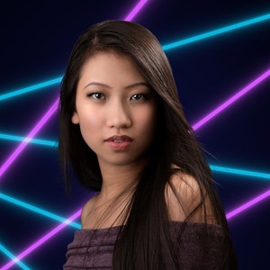 May include: A woman with long dark hair wearing a purple off-the-shoulder top stands in front of a blue and purple neon light background.
