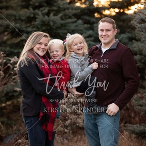 Op de afbeelding: Een gezin van vier, een moeder, een vader en twee jonge kinderen, staan voor een rij naaldbomen. De ouders houden hun kinderen vast en iedereen lacht. De ouders dragen casual kleding en de kinderen dragen kleurrijke kleding. De tekst "DO NOT SCREENSHOT OR SHARE THIS IMAGE UNTIL IT IS PAID FOR" is zichtbaar op de afbeelding.