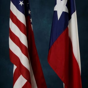 以下が含まれることがあります： 暗い青色の背景に2つの旗。左側の旗はアメリカ合衆国の国旗で、赤と白のストライプと青い背景に白い星のフィールドがあります。右側の旗はテキサス州の旗で、青いフィールドに白い星、白と赤のストライプがあります。