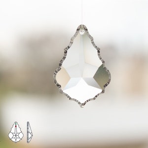 以下が含まれることがあります： ファセットデザインの透明なクリスタル製の涙型ペンダント。ペンダントは波状のエッジになっており、細い紐で吊り下げられています。